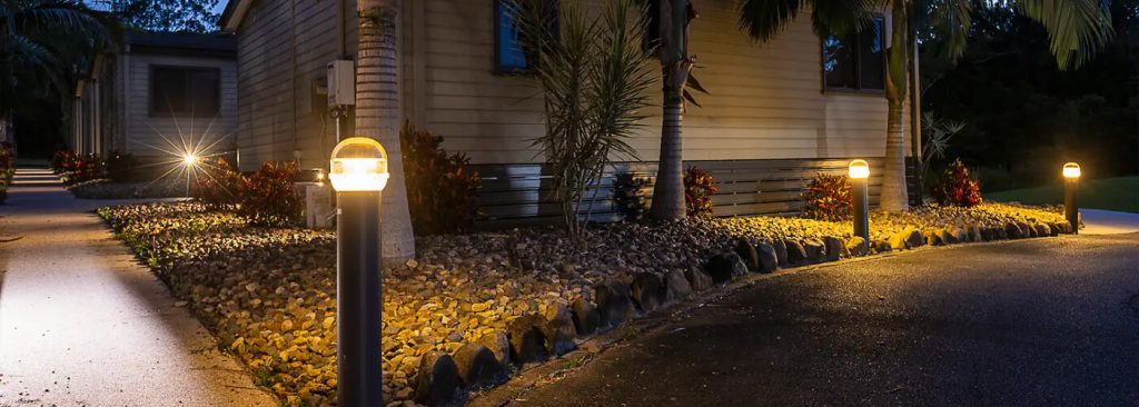 Stylish bollard lights shining on garden flower bed and path in Brisbane