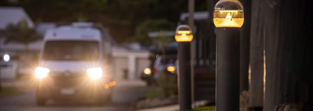 long row of bollard lights shining on a road at night to make driving safe and the road easy for drivers to see
